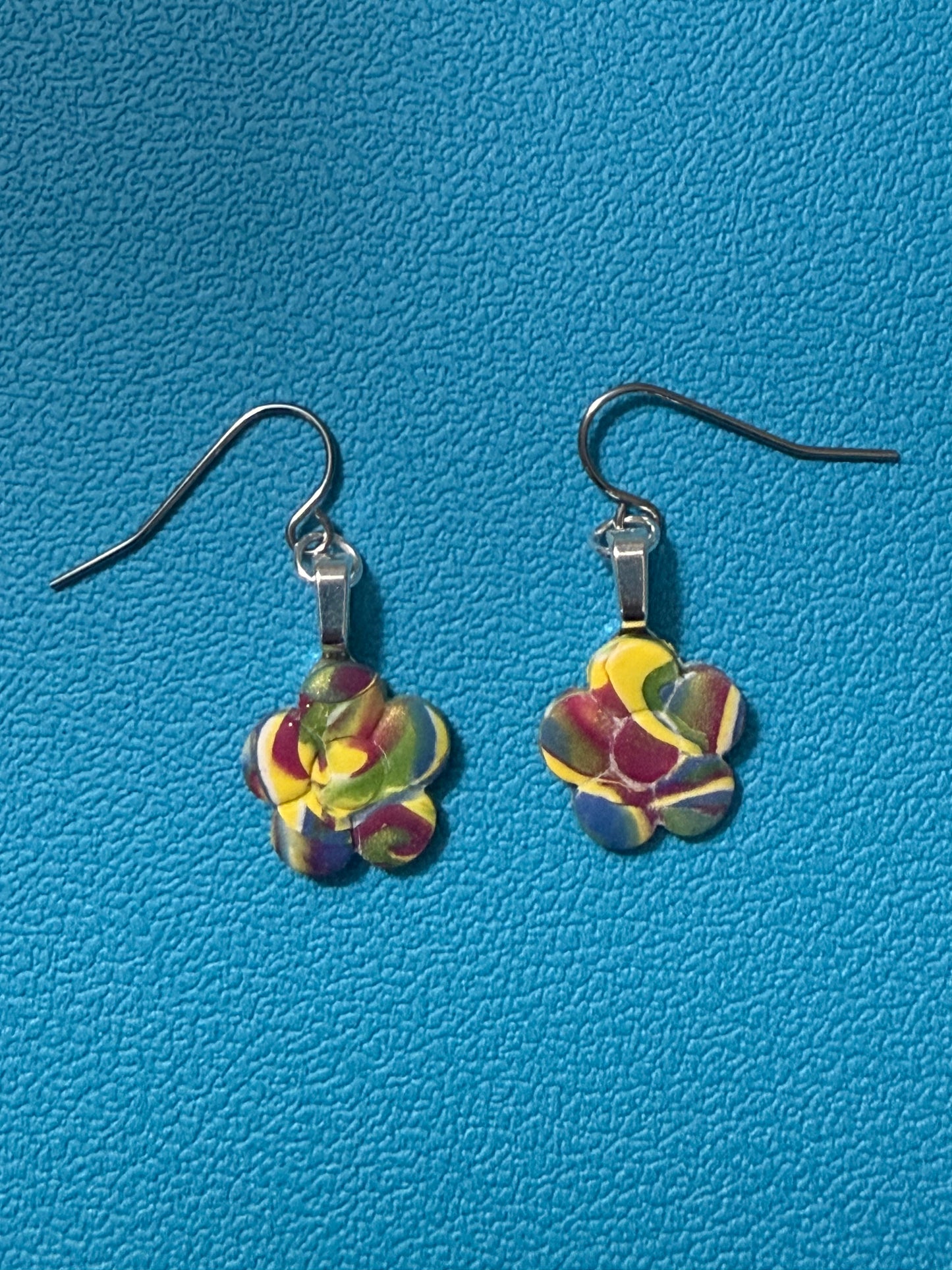 Handcrafted polymer clay flower-shaped earrings in swirled yellow, green, purple, blue, and white tones with stainless steel ear wires